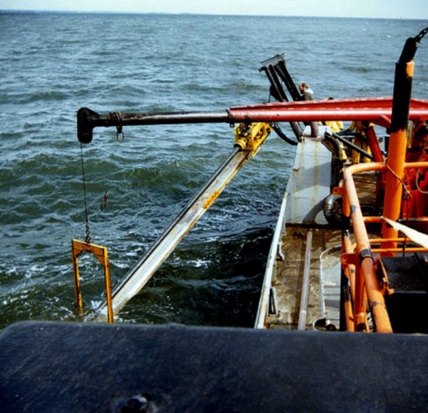 Vibracorer being swung out and rotated to the vertical position for coring. An unused plastic core liner, with an empty core cutter attached, is positioned on the deck in preparation for the next core.