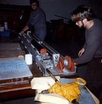 An unidentified technician uses the core-splitting machine to draw a knife blade through opposite sides of the plastic core liner at Woods Hole Oceanographic Institution (WHOI).