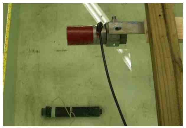 Figure 28A.  An Imagenex 881A imaging sonar in a laboratory test tank. The red end of the transducer is the source of the sonar signal. The object in the bottom of the figure (and tank) is a target along the sonar's path. 